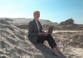 freelance and remote work.business woman in stylish business suit with laptop sitting in desert sand. Female student online training education abroad