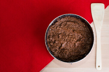 Raw brownie in mold and wooden spatula