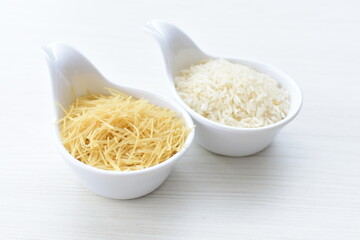 Short pasta spaghetti angel hair and uncooked rice displayed in containers on white background