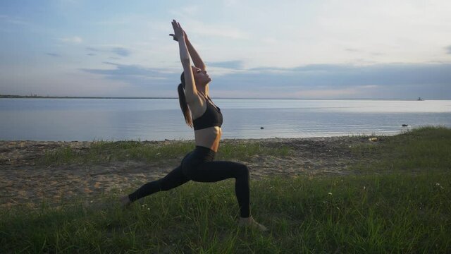 young athletic girl is engaged in yoga warrior pose outdoor