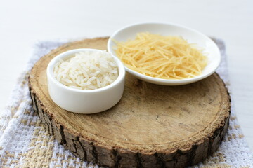 Short pasta spaghetti angel hair and uncooked rice displayed in containers on white background