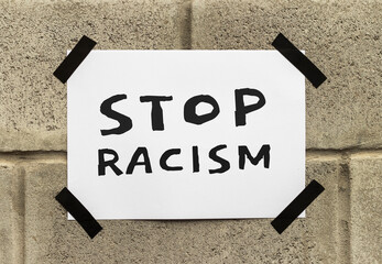 Black poster on gray brick wall. Banner with text Stop Racism. Black Lives Matter. Anti-racism...