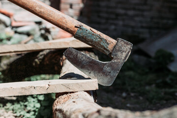 Old metal axe stuck in the wooden plank. Hard manual work