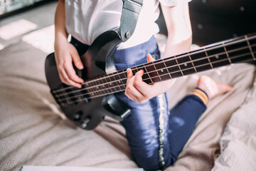 Fototapeta na wymiar close up on the fingers of young girl playing bass guitar