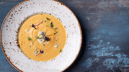 Top view of  pumpkin soup with blue cheese on a plate. Text space