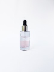 Cosmetic glass bottle with liquid inside and pipette, black rubber cap on a white background close-up.