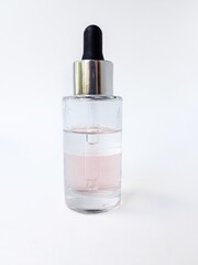 Naklejka premium Cosmetic glass bottle with liquid inside and pipette, black rubber cap on a white background close-up.