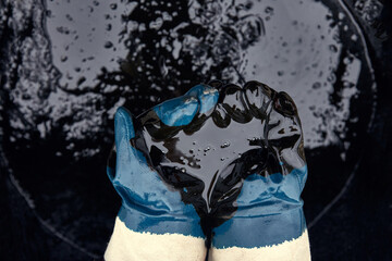 Rubber gloves soaked in oil on the background of spilled oil. Crisis of the oil industry. Economic downturn. Black gold.
