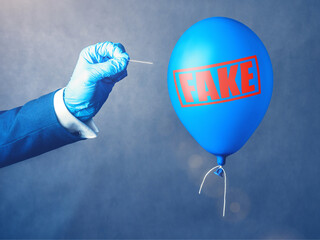 Concept of fake information. Blue balloon. Man hold needle directed to air balloon. Idea of disinformation and propaganda