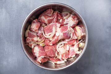 Pork meat with onion, salt and pepper. Raw pork ready to cook on ckewers in a bowl. Marinated meat. Shashlik. Top view