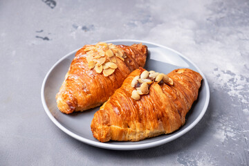 Fresh bakery croissants on a plate. ?roissants  with almond flakes and nuts.
