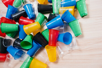 A large pile of multicolored plastic cups scattered on the floor. Pollution of the environment by...