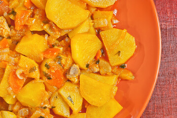 Potatoes in a garlic plate on a wooden table. Boiled potatoes with orange sauce.