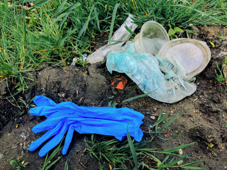 Fototapeta na wymiar Disposable medical gloves on ground with single use plastic trash. How to dispose used medical gloves right after coronavirus pandemic. Do not throw them away