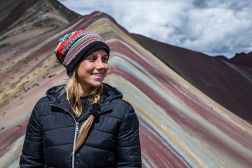 beautiful blonde woman in the rainbow mountain in peru. 7 color mountain.