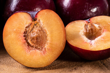 .Plum cut in half with some plums in the background. Wood background