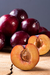 .Plum cut in half with some plums in the background. Wood background