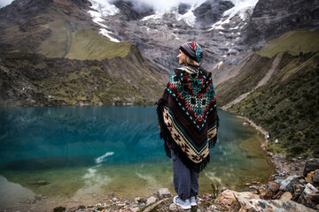 Beautiful blonde woman standing by a turquoise lake in the mountains