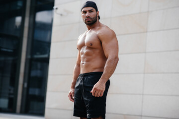 sexy sportsman stands topless near the wall. Fitness, bodybuilding