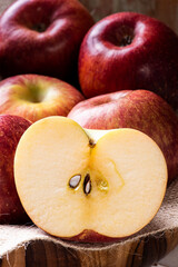 .Apple cut in half with some apples in a basket in the background. Wood background