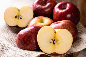 .Apple cut in half with some apples in a basket in the background. Wood background