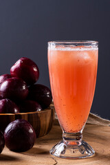 Glass of plum juice with some plums in the background