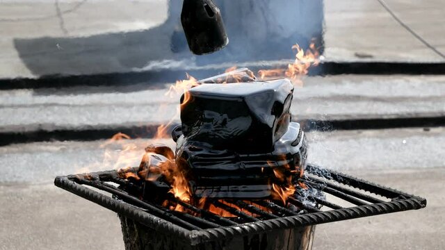 A worker melts tar with help of gas burner and fire. Pieces of bitumen are melted in bucket. Roof repair
