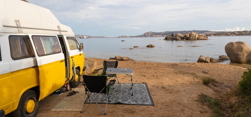 Tourism vacation and travel. Old colorful retro camper van on camping site at beautiful rocky coastal landscape ofnorth east Sardinia, Italy.