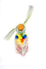 Selective Focus shot where only top cork is in focus of bottle filled with multi colored candy topped with a cork and tied with ribbon on white background