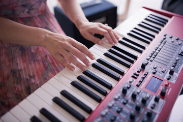 Obraz premium Woman wearing pink dress with hands on red piano keyboard