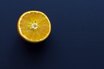 half an orange on a dark blue painted background