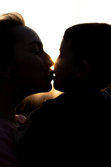 Silhouette of a mother and son playing outdoors at sunset. Mother's day concept