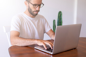 Young man with screen glasses typing on the computer