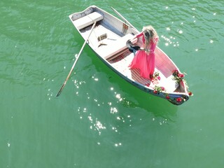 Romantic woman with long blond hair on boat with roses and flower