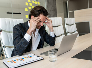 Shot of a young businessman looking displeased while using a computer at his work desk