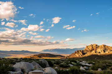 Obraz premium white cloud hangs in blue sky above rocky desert plain with distant view of hills, valley and mountain range in Sierra Nevada mountains of California