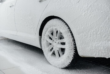 Modern washing of car wheels with foam and high water pressure. Car wash