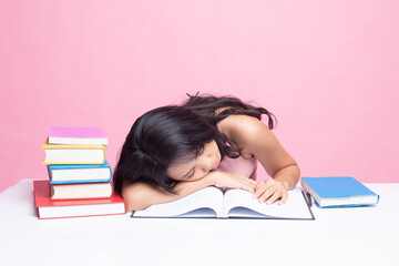 Exhausted Young Asian woman sleep with books on table.