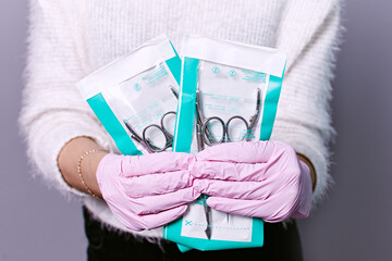 Manicure set in the salon. Sterilization of instruments. Hands in pink gloves holding manicure...