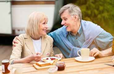 Loving senior couple having toasts with jam for breakfast at campground
