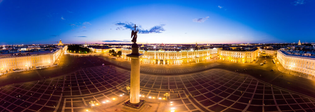 Aerial panoramic view to Winter Palace building and Square in summer white night. Angel on Aleksandr Column is symbol peace on Europe. Top view from drone with cloudy background, St. Petersburg Russia