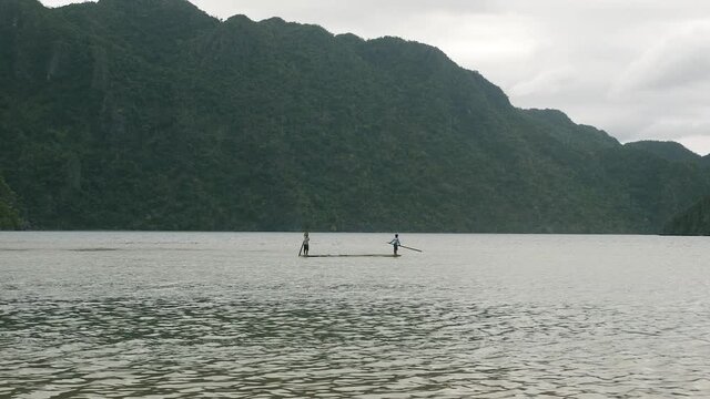 Two people paddle boarding on a bay in Asia