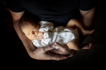 Father holding his 15 days old son in his hand on black background