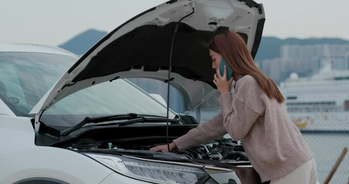 Woman call for help on cellphone with car problem on street