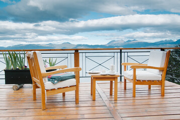 Beautiful panoramic views of the Beagle Channel and the mountains, from  abalcony with arranged table and seat and tea cups.