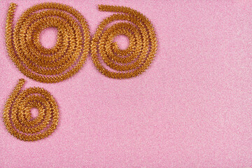 Fashion composition with golden serpentine on pink. Birthday, Christmas, holiday, wedding, celebration, New Years Eve, Festive concept. Empty copy space for text. Greeting card or invitation. Flatlay