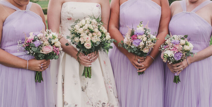 Bride and three bridesmaid close up of arms with flowers in lilac and white