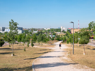 Obraz premium People walking and playing sports on the path of a park during the coronavirus alarm state. Near the Infanta Sofia hospital