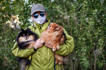 A girl wearing respirator mask walking with Pomeranian dogs in the forest protecting from COVID-19.