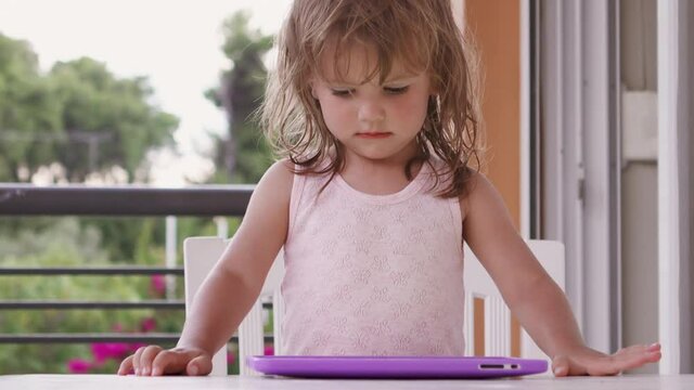 Cute little girl watching tablet on the terrace
